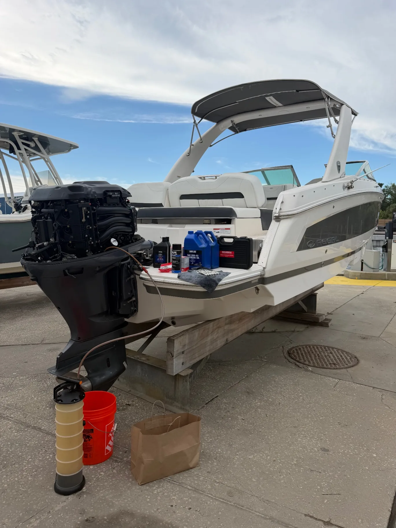 Technician servicing an outboard engine on a boat at a dry-stack marina
