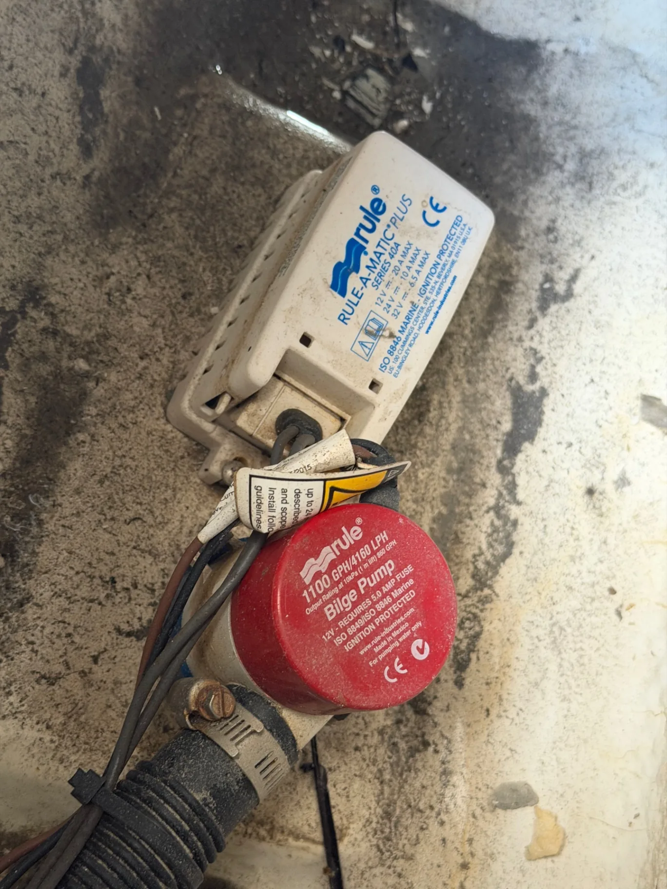 Bilge pump and automatic float switch being inspected inside a boat bilge